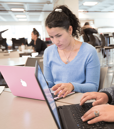 多诺万餐饮中心的女学生正在用粉红色的笔记本电脑工作 