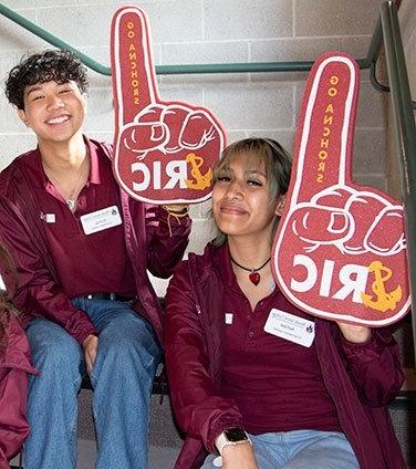 Two orientation leaders smiling, with RIC foam fingers
