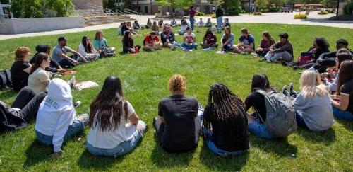迎新时，一群学生围成一圈坐在草地上